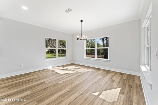 unfurnished dining area featuring ornamental molding, an inviting chandelier, and light wood-type flooring