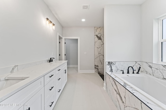 bathroom with vanity and tiled tub