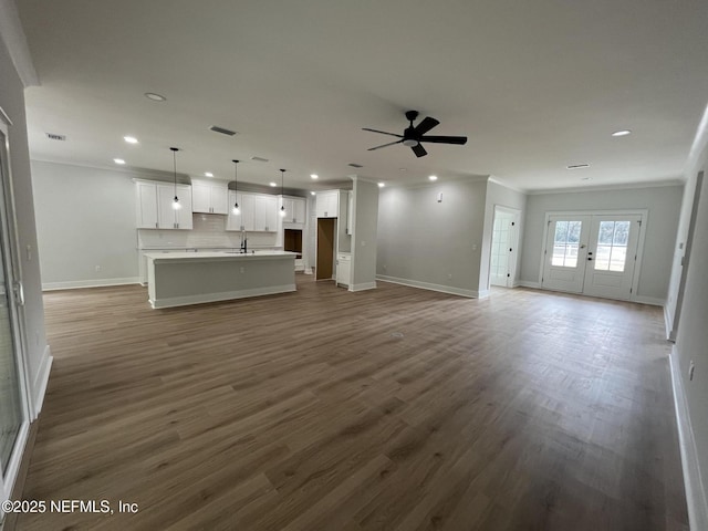 unfurnished living room featuring crown molding, ceiling fan, dark hardwood / wood-style floors, and french doors