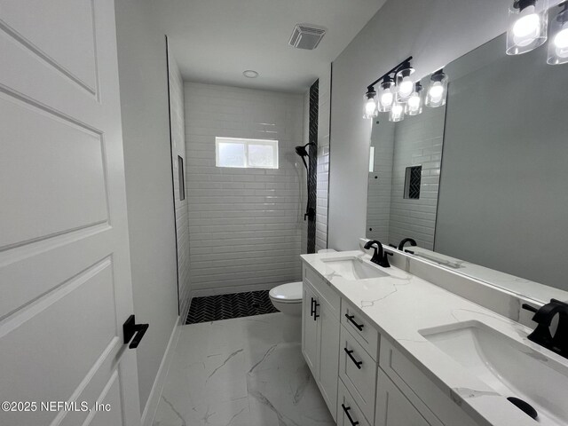 bathroom with vanity, a tile shower, and toilet