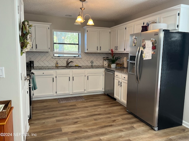 kitchen featuring sink, white cabinetry, stainless steel appliances, and an inviting chandelier