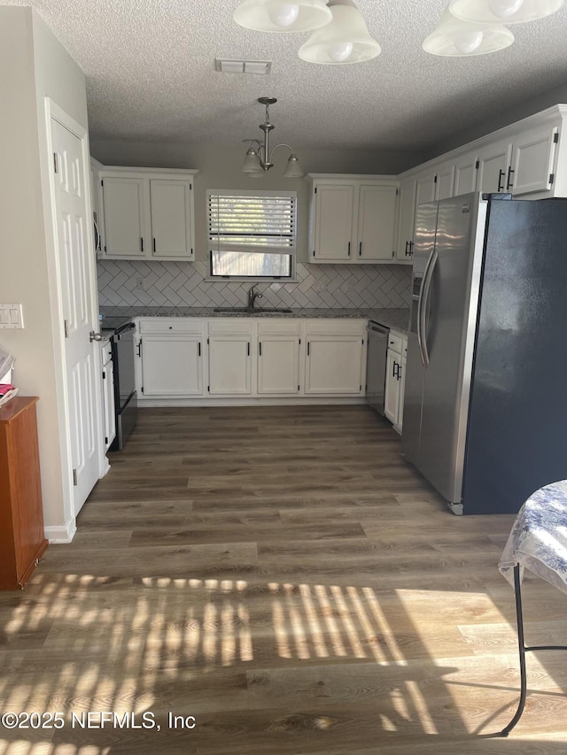 kitchen with white cabinets, dark hardwood / wood-style flooring, backsplash, and appliances with stainless steel finishes