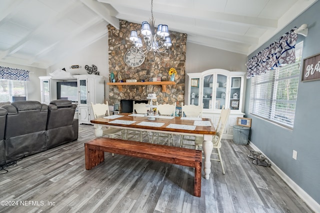 dining space featuring hardwood / wood-style floors, plenty of natural light, lofted ceiling with beams, and a stone fireplace