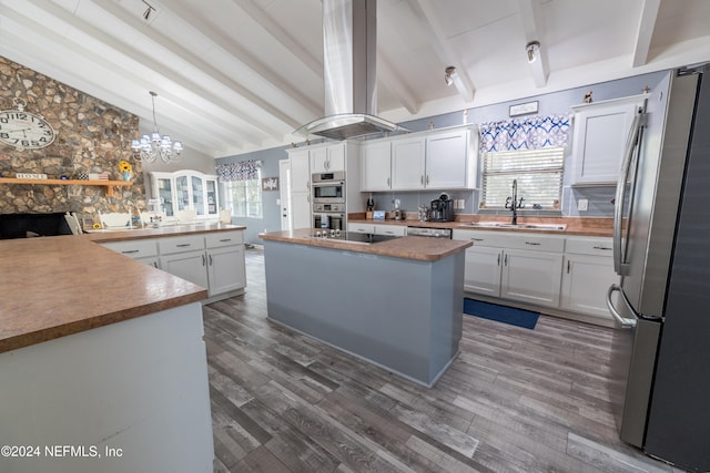 kitchen featuring white cabinets, appliances with stainless steel finishes, vaulted ceiling with beams, and a center island