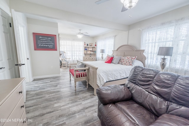 bedroom with beam ceiling, light wood-type flooring, and ceiling fan