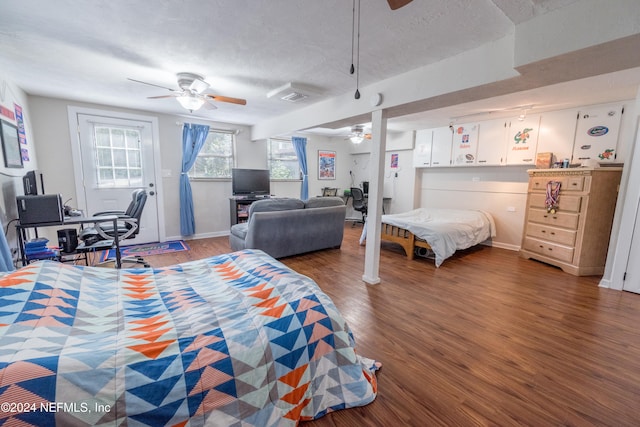 bedroom with a textured ceiling, dark hardwood / wood-style flooring, and ceiling fan