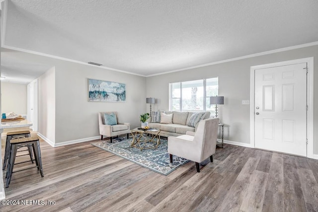 living room with a textured ceiling, hardwood / wood-style flooring, and crown molding