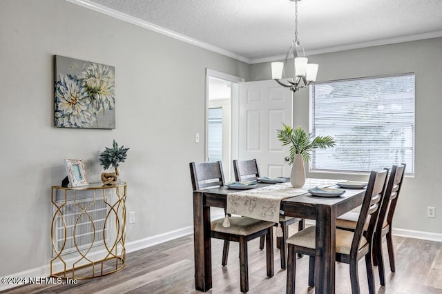 dining room featuring a notable chandelier, ornamental molding, a textured ceiling, and hardwood / wood-style flooring