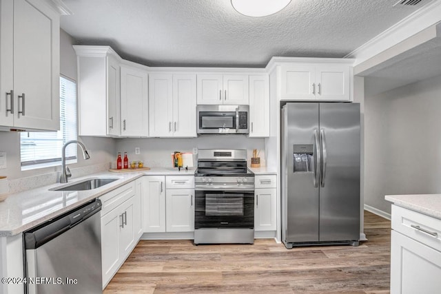 kitchen with white cabinetry, sink, stainless steel appliances, light hardwood / wood-style floors, and a textured ceiling