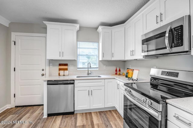 kitchen with white cabinetry, sink, appliances with stainless steel finishes, and light hardwood / wood-style flooring