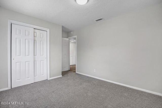 unfurnished bedroom with carpet flooring, a textured ceiling, and a closet