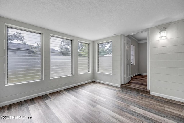 unfurnished room featuring crown molding, wood-type flooring, and a textured ceiling