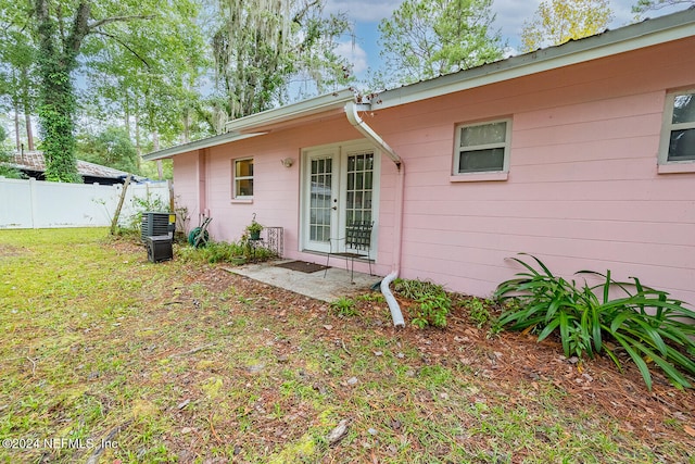 rear view of property with central air condition unit and a yard