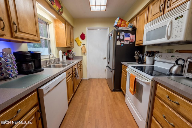 kitchen with light wood-type flooring, white appliances, and sink