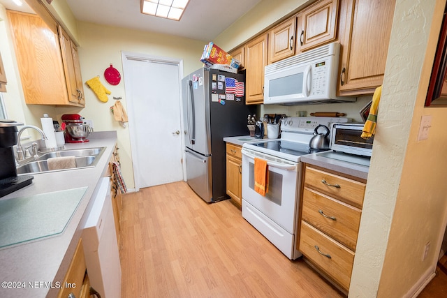 kitchen featuring sink, white appliances, and light wood-type flooring