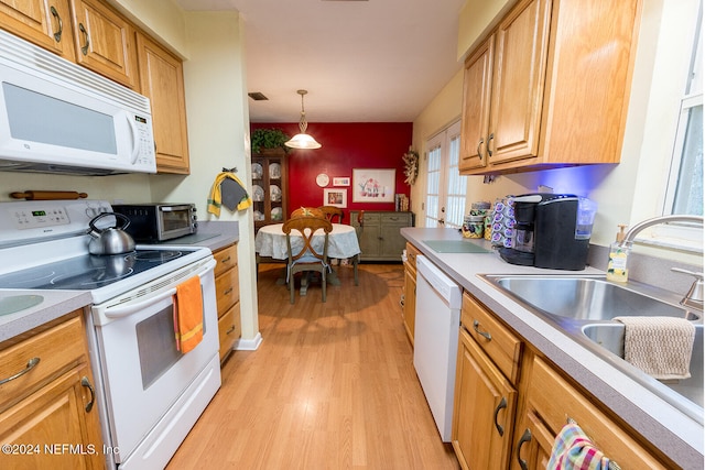 kitchen featuring light hardwood / wood-style flooring, decorative light fixtures, white appliances, and sink