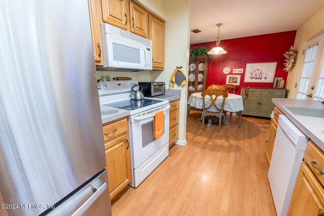 kitchen featuring light hardwood / wood-style flooring, decorative light fixtures, white appliances, and sink