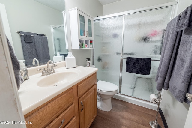 bathroom with toilet, hardwood / wood-style floors, vanity, and walk in shower