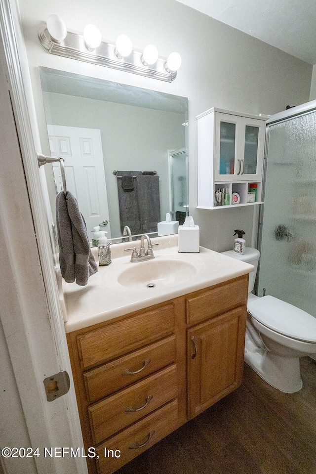 bathroom with hardwood / wood-style floors, vanity, toilet, and an enclosed shower