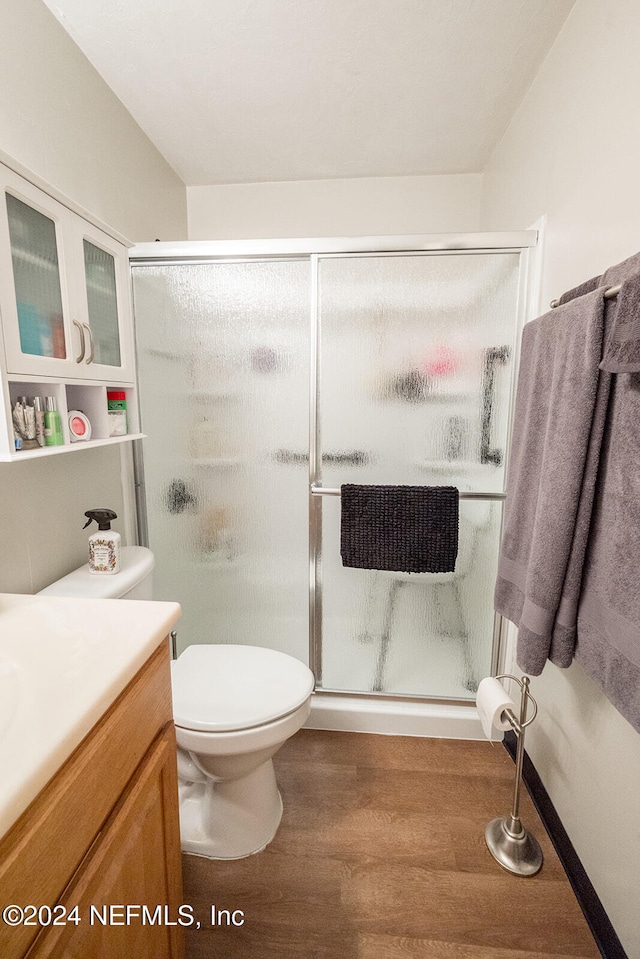 bathroom featuring vanity, toilet, wood-type flooring, and a shower with door