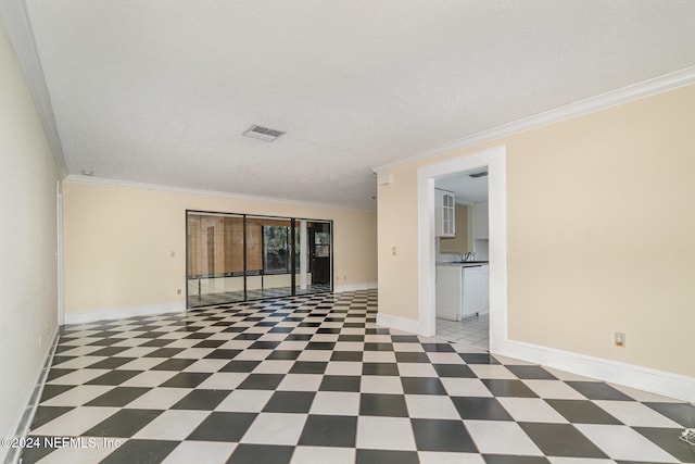 spare room with a textured ceiling and crown molding