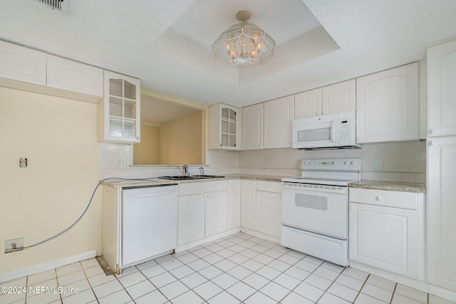 kitchen featuring a raised ceiling, white cabinetry, sink, and white appliances