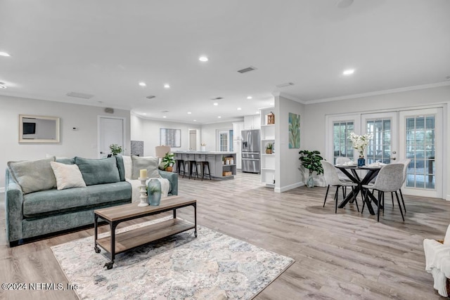 living room with light hardwood / wood-style floors, ornamental molding, and french doors