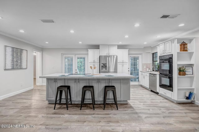 kitchen with a kitchen breakfast bar, stainless steel appliances, white cabinetry, and a large island