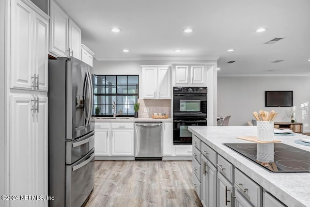 kitchen with black appliances, light hardwood / wood-style floors, white cabinets, and ornamental molding