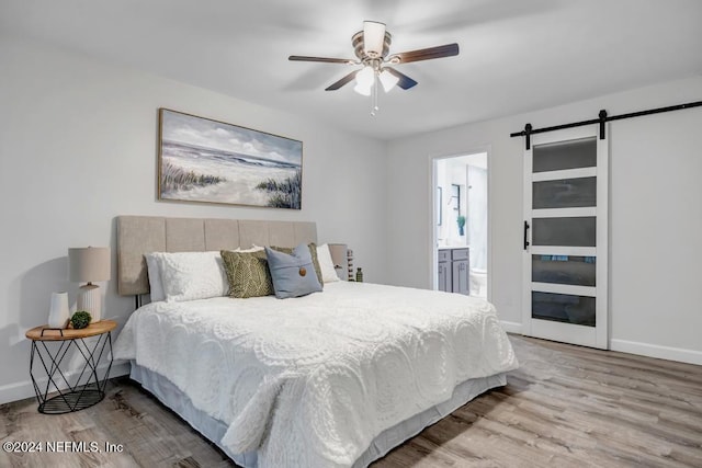 bedroom with connected bathroom, ceiling fan, hardwood / wood-style floors, and a barn door