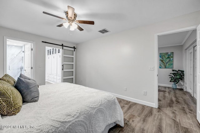 bedroom featuring hardwood / wood-style flooring, ceiling fan, and a barn door