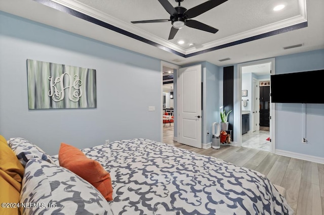 bedroom with a raised ceiling, ceiling fan, and light hardwood / wood-style floors