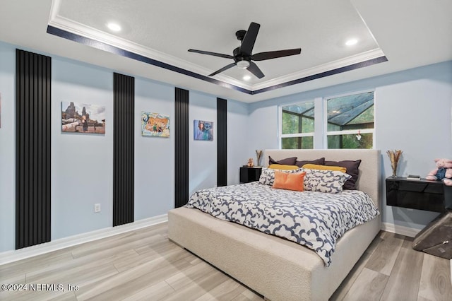 bedroom with a tray ceiling, light hardwood / wood-style flooring, ceiling fan, and ornamental molding