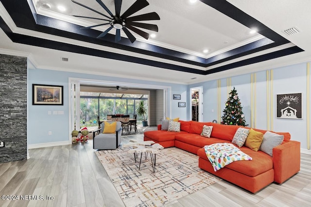 living room featuring wood-type flooring, a raised ceiling, ceiling fan, and crown molding