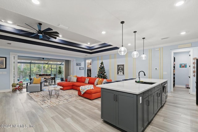 kitchen with decorative light fixtures, a center island with sink, ornamental molding, and sink