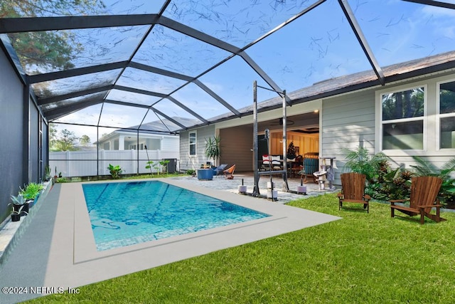 view of pool featuring glass enclosure, a patio area, and a lawn