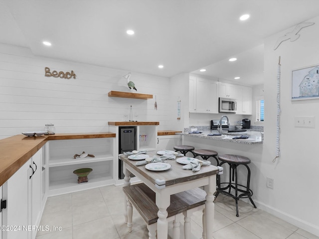 kitchen with appliances with stainless steel finishes, white cabinetry, light stone counters, and light tile patterned floors