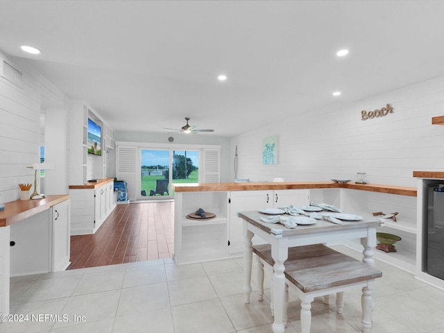 dining area featuring ceiling fan, wood walls, and light tile patterned floors