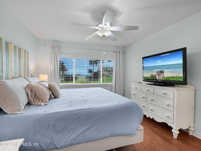 bedroom with a textured ceiling, ceiling fan, and dark wood-type flooring