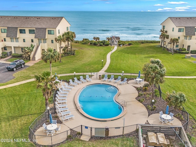 view of pool featuring a patio, a water view, and a yard