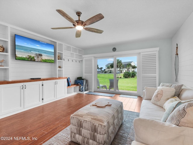 living room with built in features, ceiling fan, and hardwood / wood-style floors