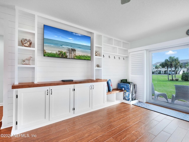 interior space with a textured ceiling, light hardwood / wood-style flooring, and built in features