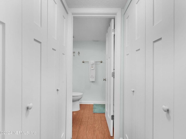 bathroom with a textured ceiling, hardwood / wood-style floors, and toilet