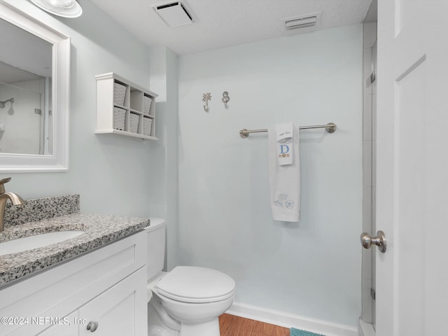 bathroom featuring toilet, vanity, hardwood / wood-style flooring, and walk in shower