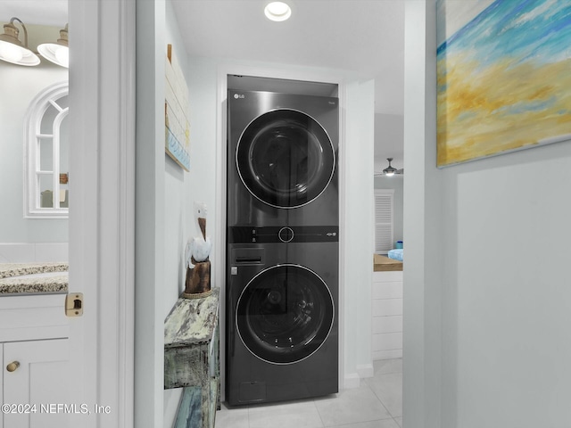 clothes washing area with light tile patterned flooring and stacked washer / dryer