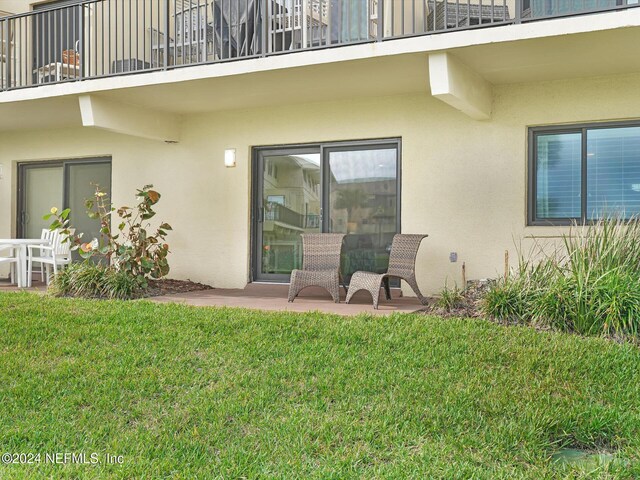 8550 A1A S Unit 13131, Saint Augustine, FL 32080 - back of house featuring stucco siding, a balcony, a lawn, and a patio