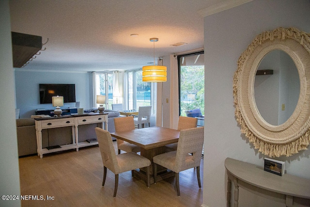 dining room featuring crown molding, a textured ceiling, and hardwood / wood-style flooring