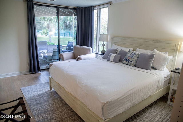 bedroom featuring multiple windows, hardwood / wood-style floors, and access to exterior