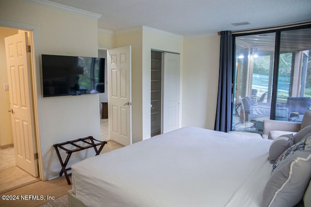 bedroom featuring access to exterior, ornamental molding, a textured ceiling, a closet, and light tile patterned flooring