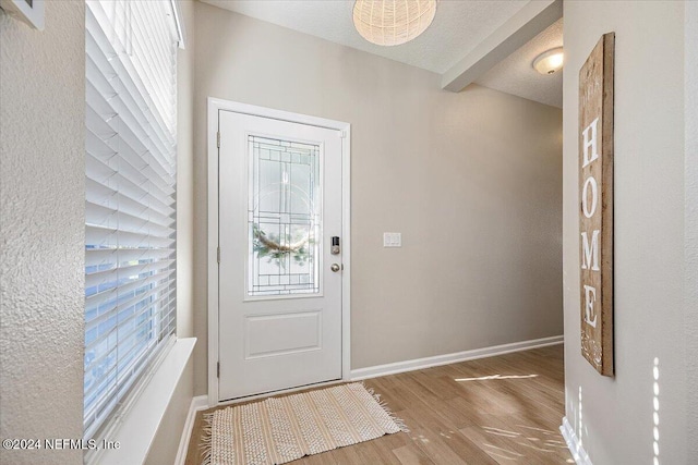 entrance foyer with beamed ceiling, wood-type flooring, and a textured ceiling